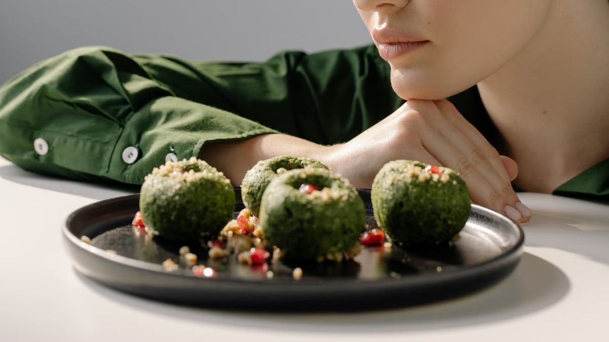 Close-up of spinach pkhali, a Georgian vegan dish, with a woman in green observing.