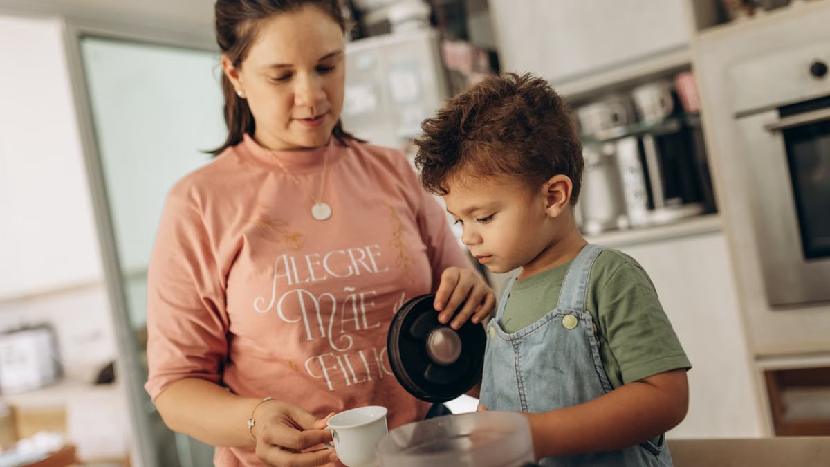 Mother and son enjoying kitchen time, pouring beverage together.